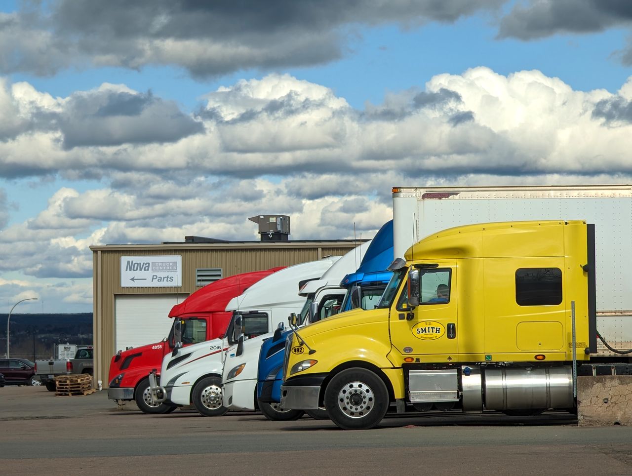 About Parked semi-trucks of various colors outside a Nova Parts warehouse in Truro, NS.