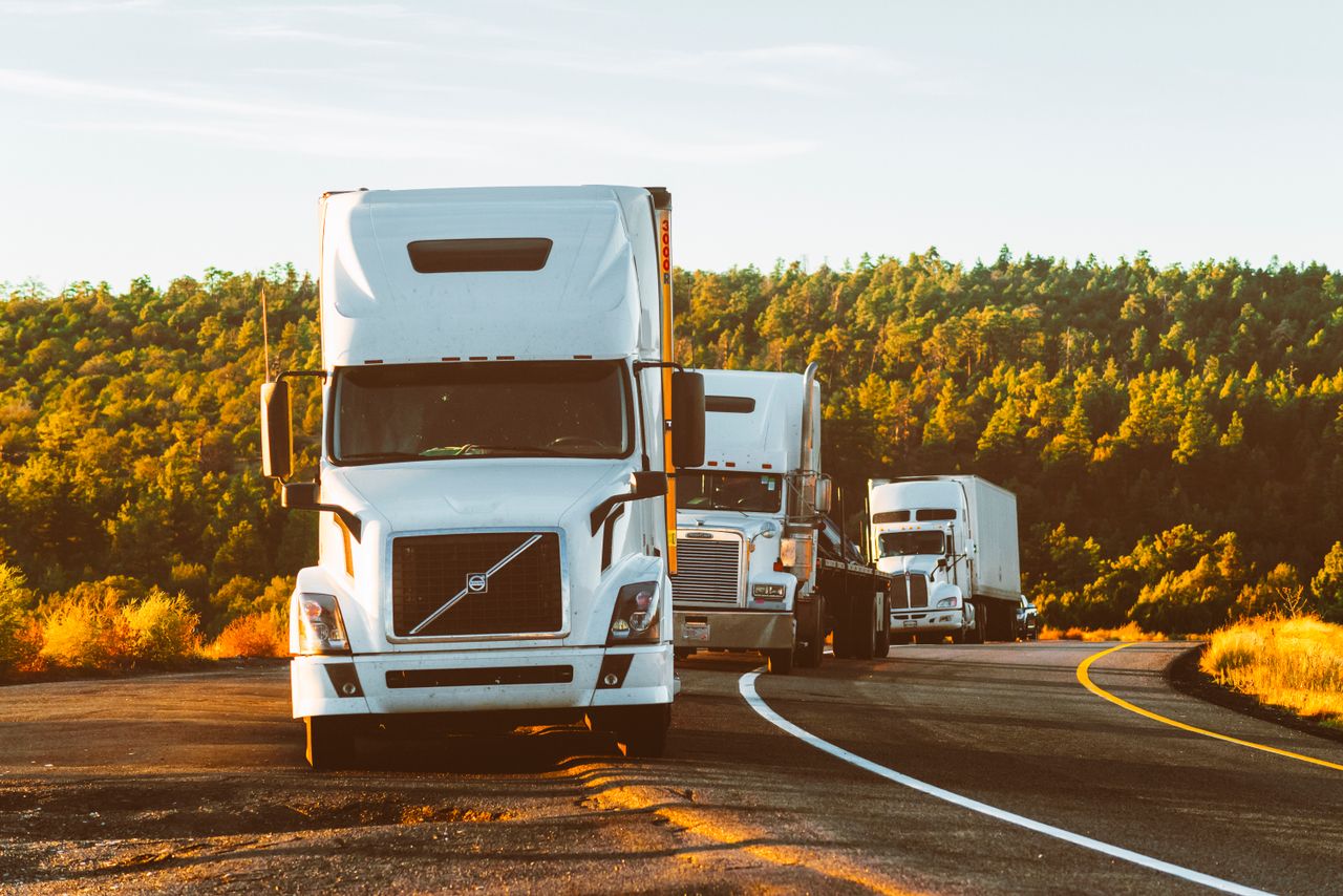 About Three semi trucks driving on a highway through a forested landscape in Arizona.